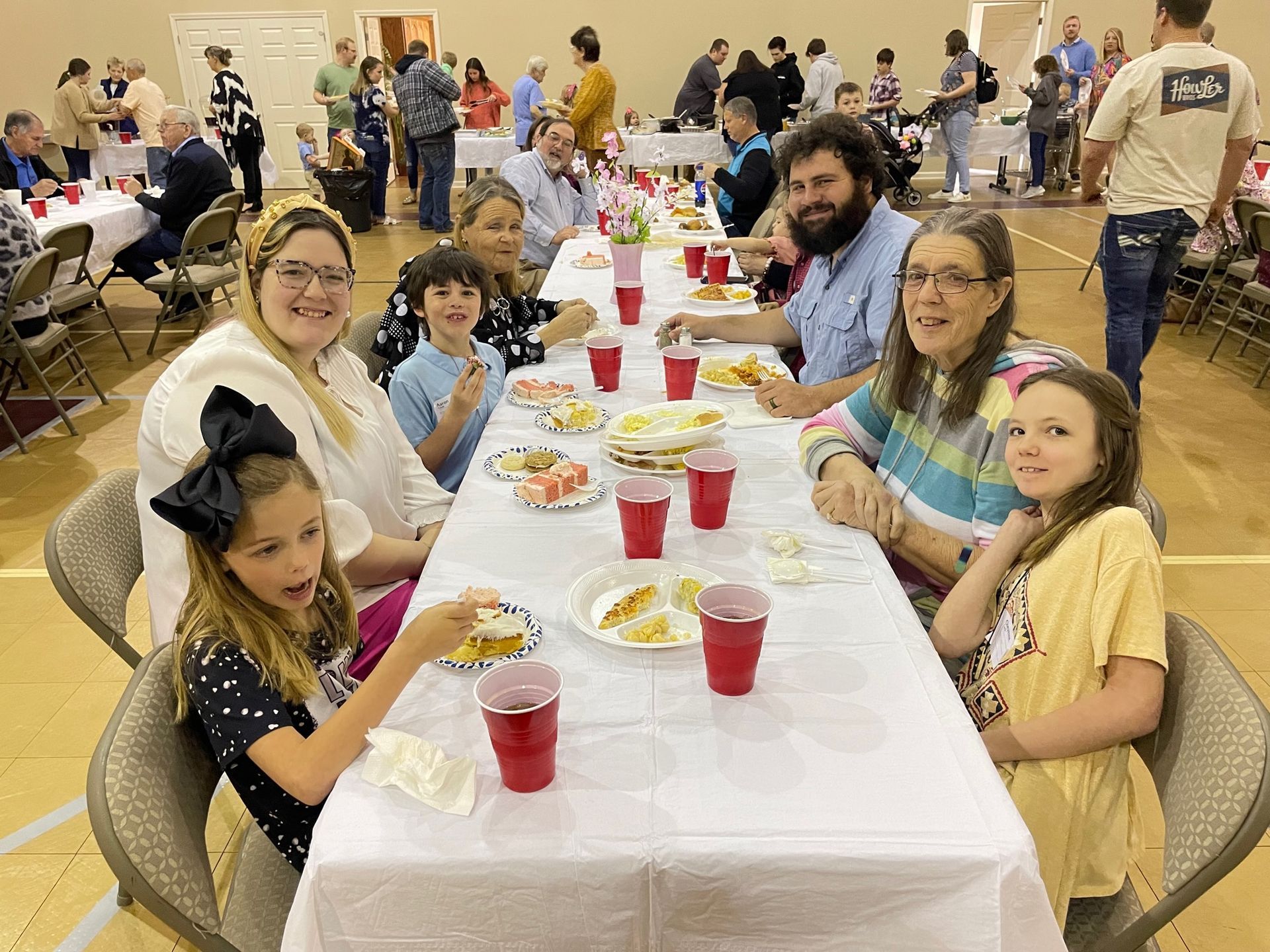 A group of people are sitting at a long table eating food.