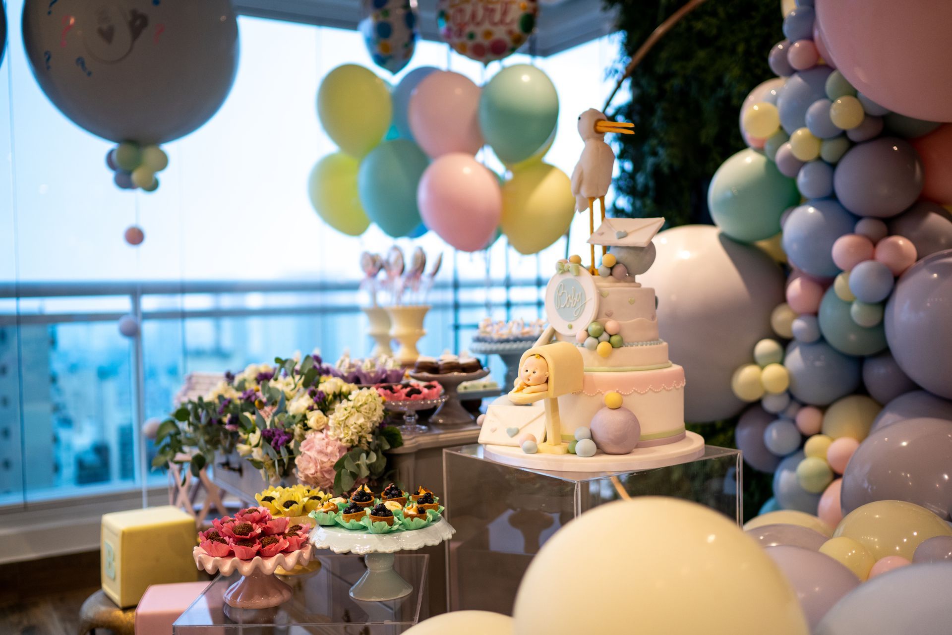 A table decorated with balloons and cakes for a baby shower.