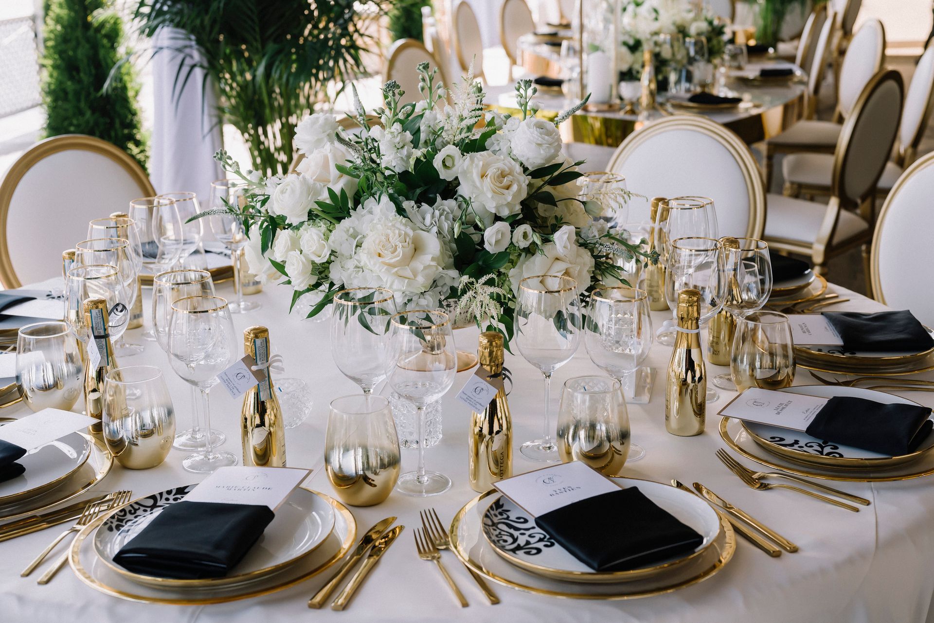 A table set for a wedding reception with plates , utensils , and flowers.