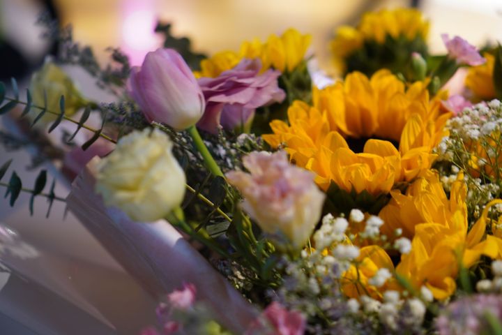 A close up of a bouquet of flowers including sunflowers and roses.