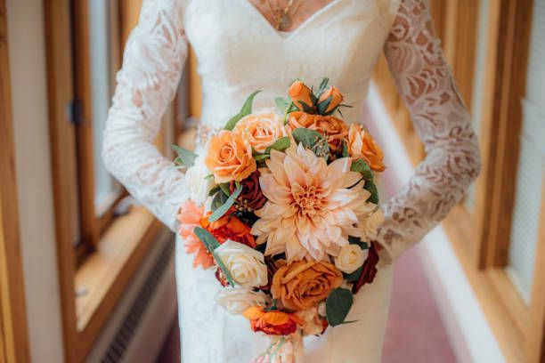 A bride in a white dress is holding a bouquet of flowers.