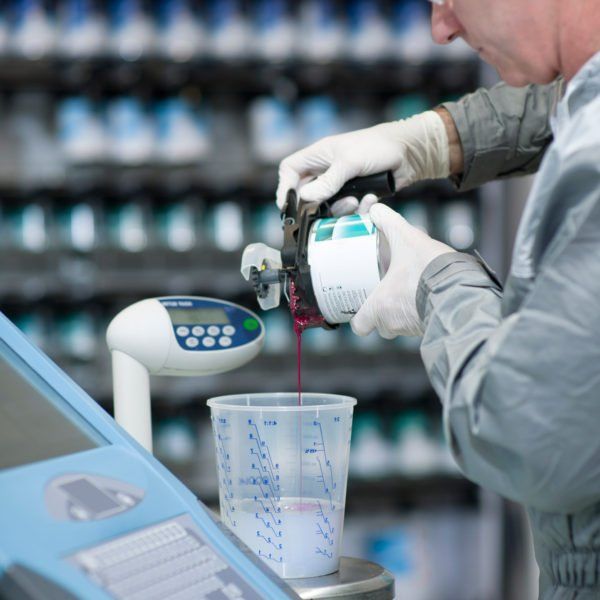 A man is pouring paint into a measuring cup