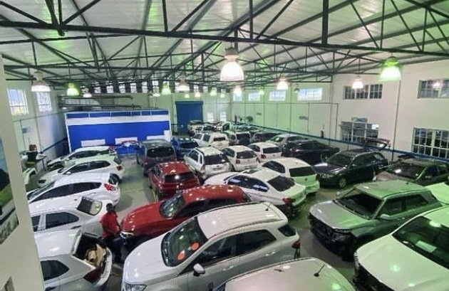 A lot of cars are parked in a warehouse.