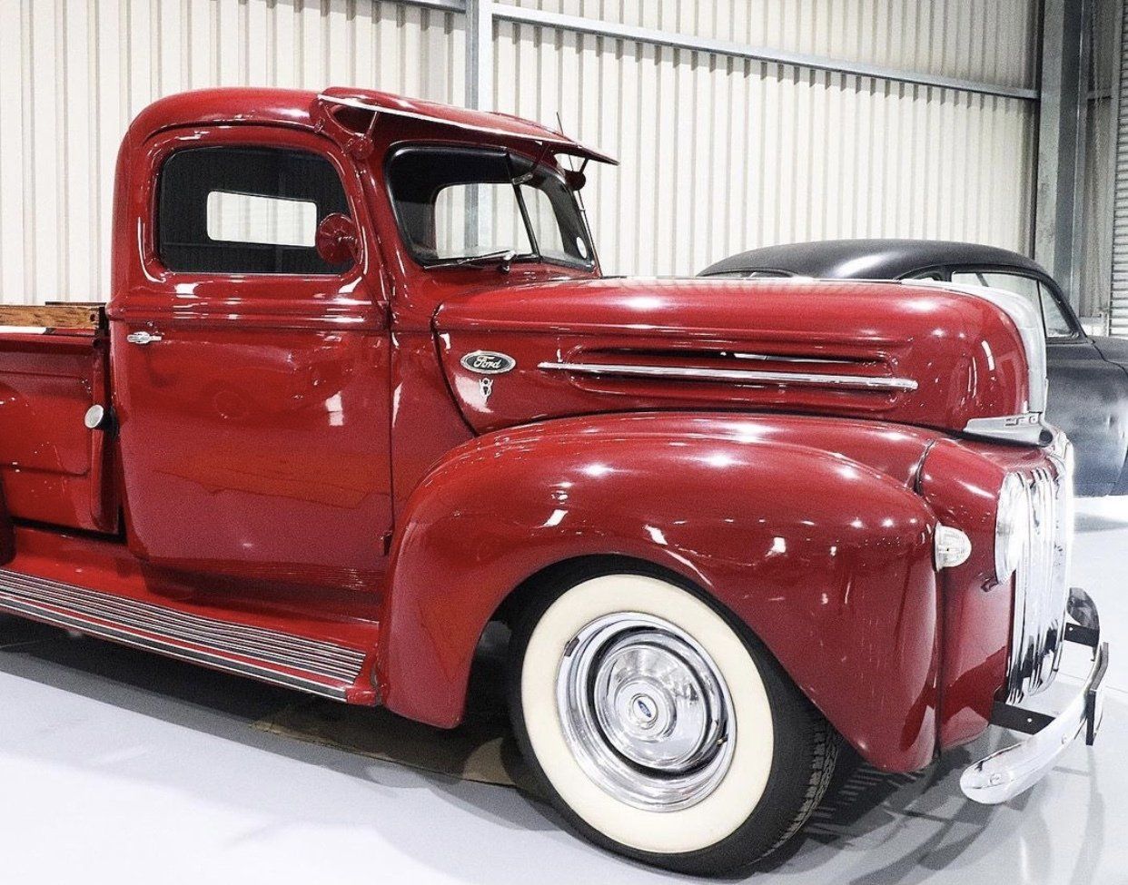 A red truck with white tires is parked in a garage.