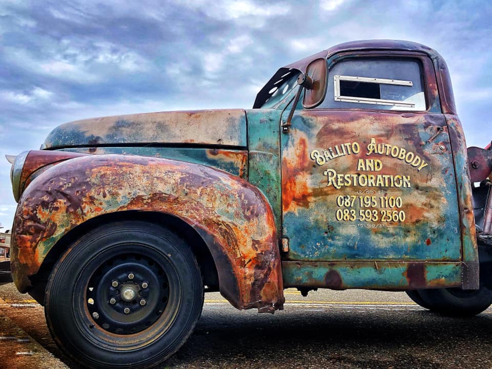 An old rusty truck is parked on the side of the road.