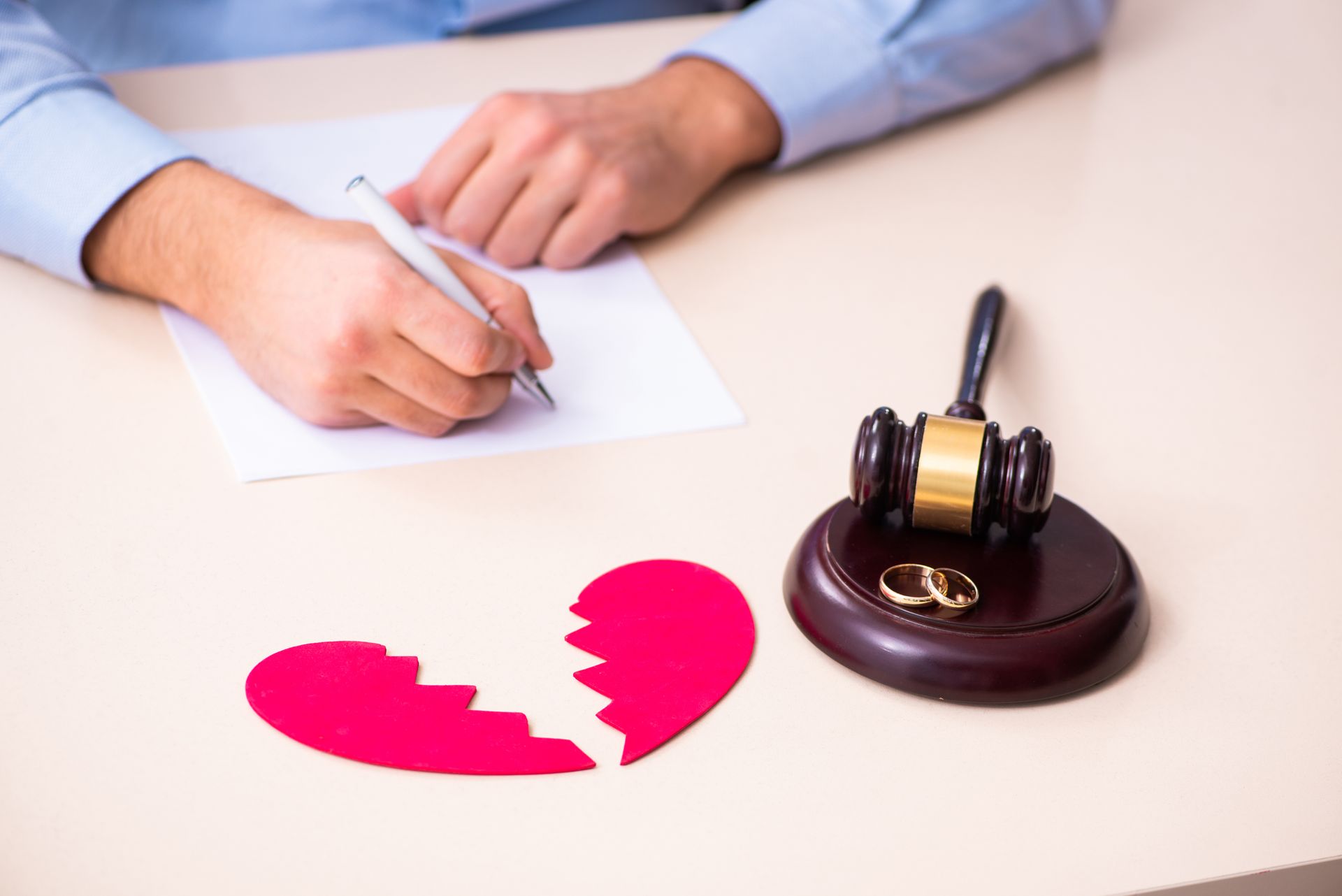 A person writing on a paper with a broken heart representing high conflict divorce in Florida.