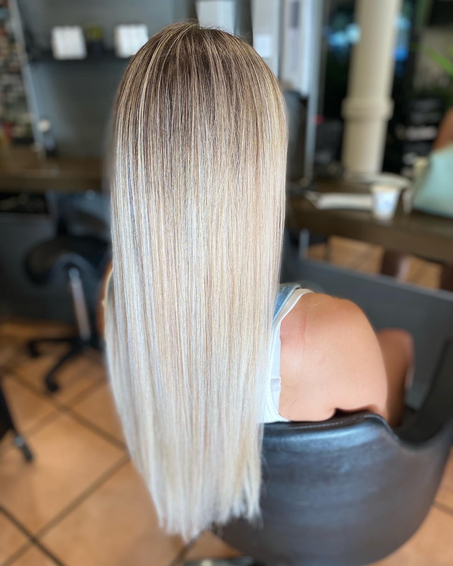 A Woman With Blonde Hair is Wearing a Black Top and Looking Down — Energy Hair Co in Sunshine Coast, QLD