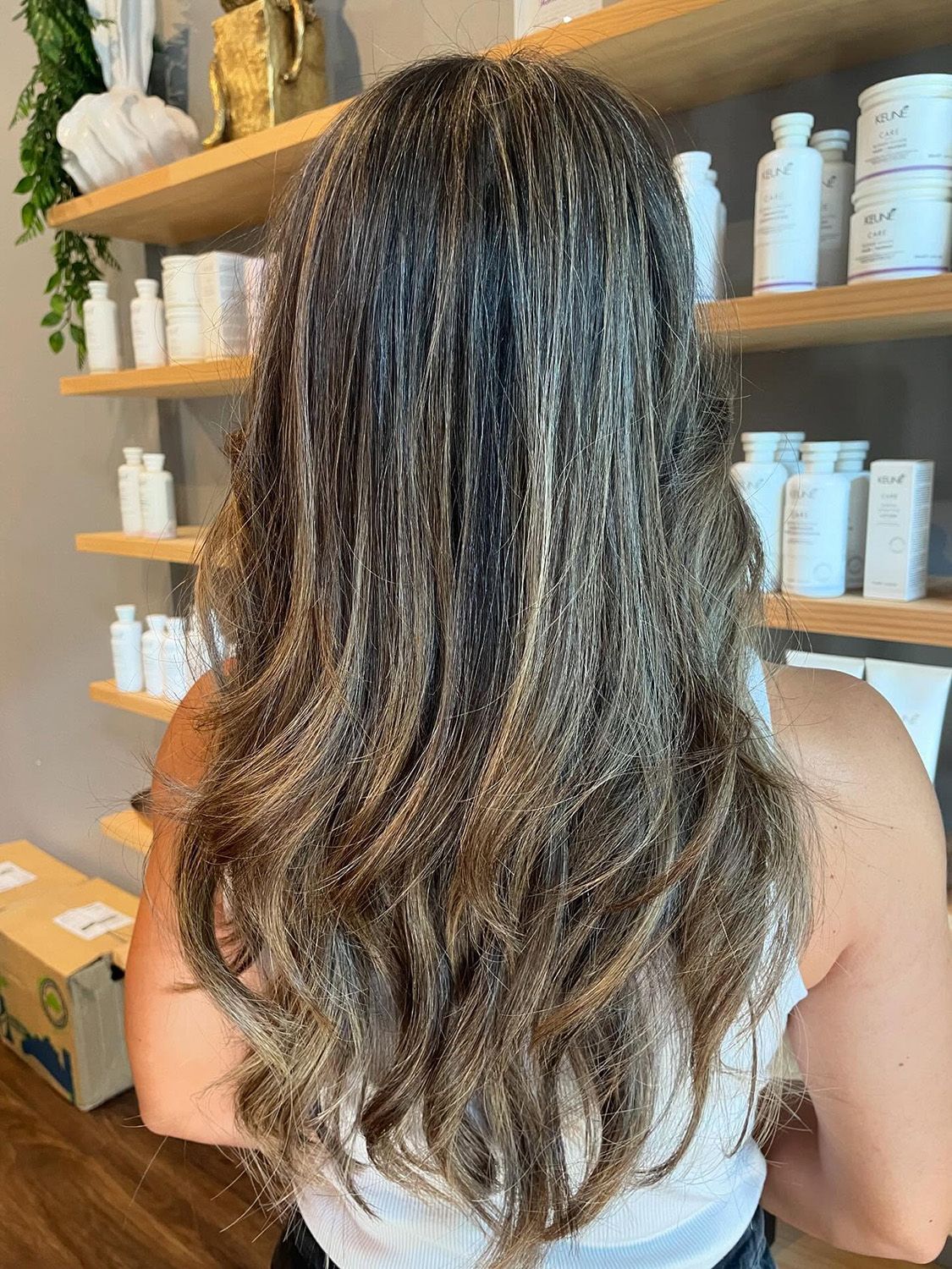 Woman with Long, Wavy Brown and Blonde Highlighted Hair Stands — Energy Hair Co in Noosa Heads, QLD