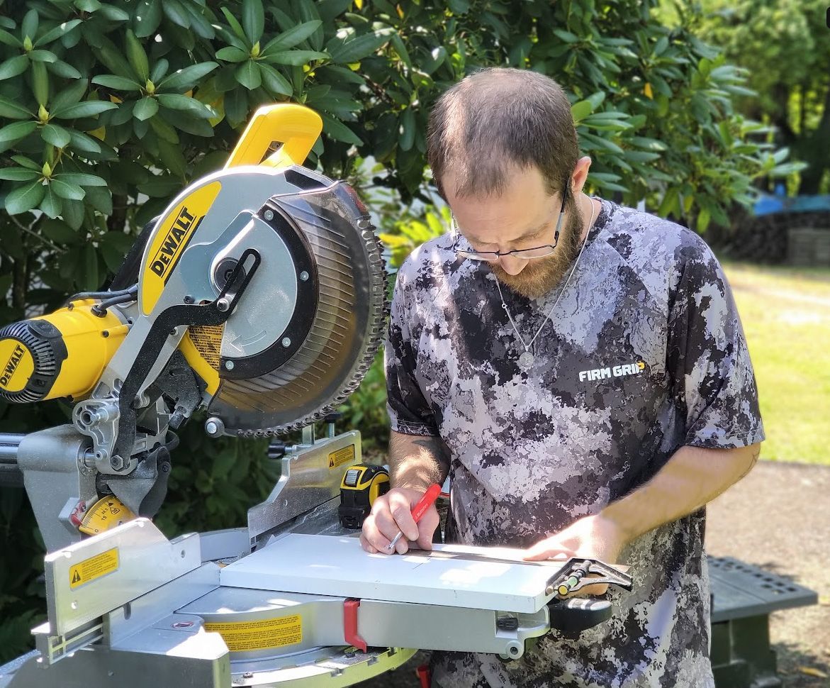 A man is using a miter saw to cut a piece of wood