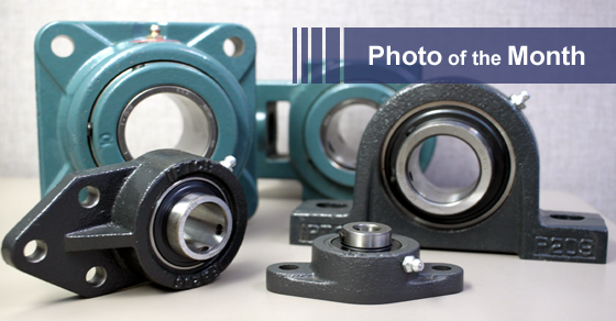 Various industrial bearings of different shapes and sizes, on a white surface. One is teal, the others are black.