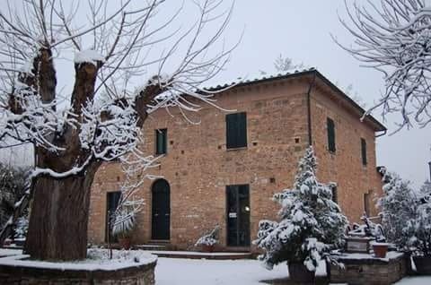 Una casa di mattoni è coperta di neve e gli alberi sono coperti di neve.