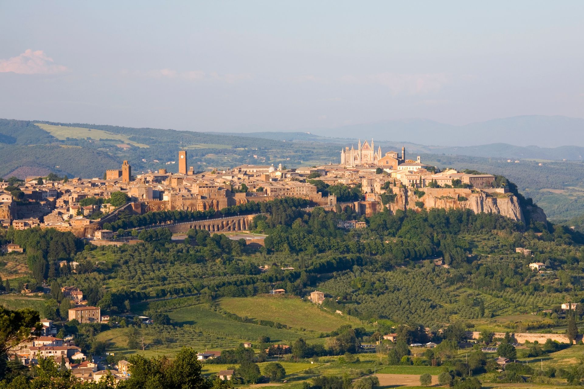 Una veduta aerea di una piccola città in cima a una collina circondata da alberi.