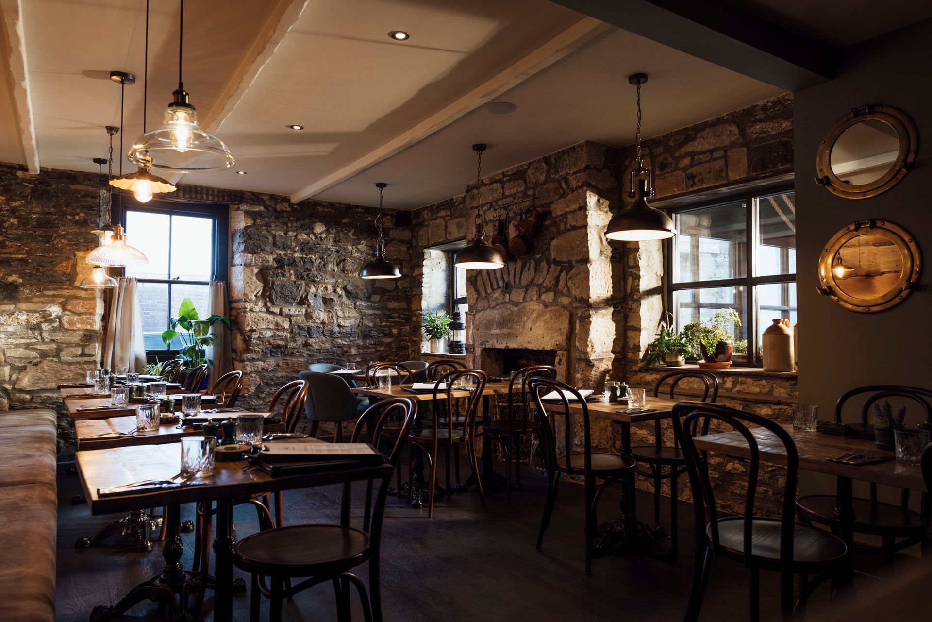 Un ristorante con tavoli, sedie e un muro di pietra.