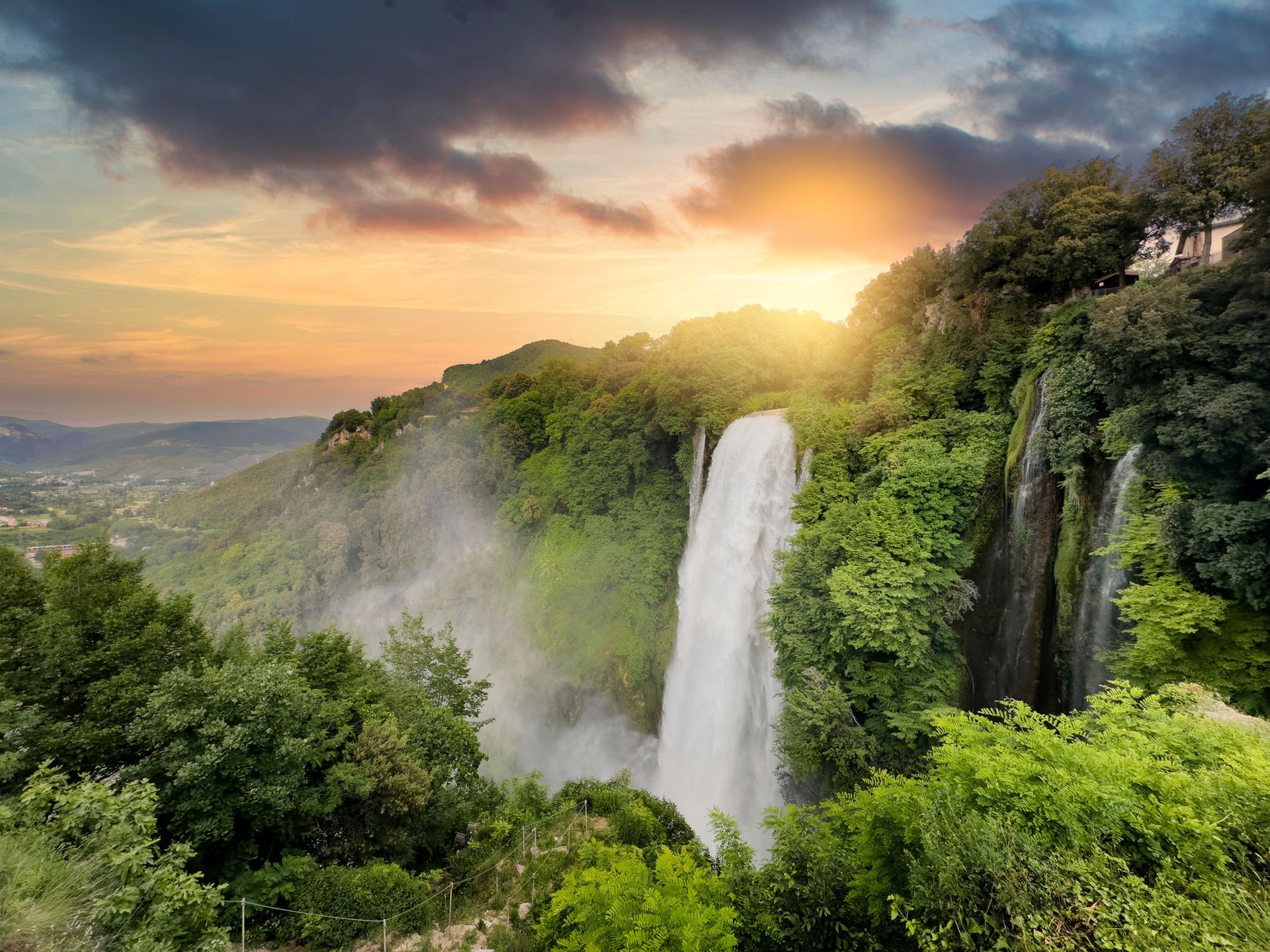 Una cascata in mezzo a una foresta al tramonto
