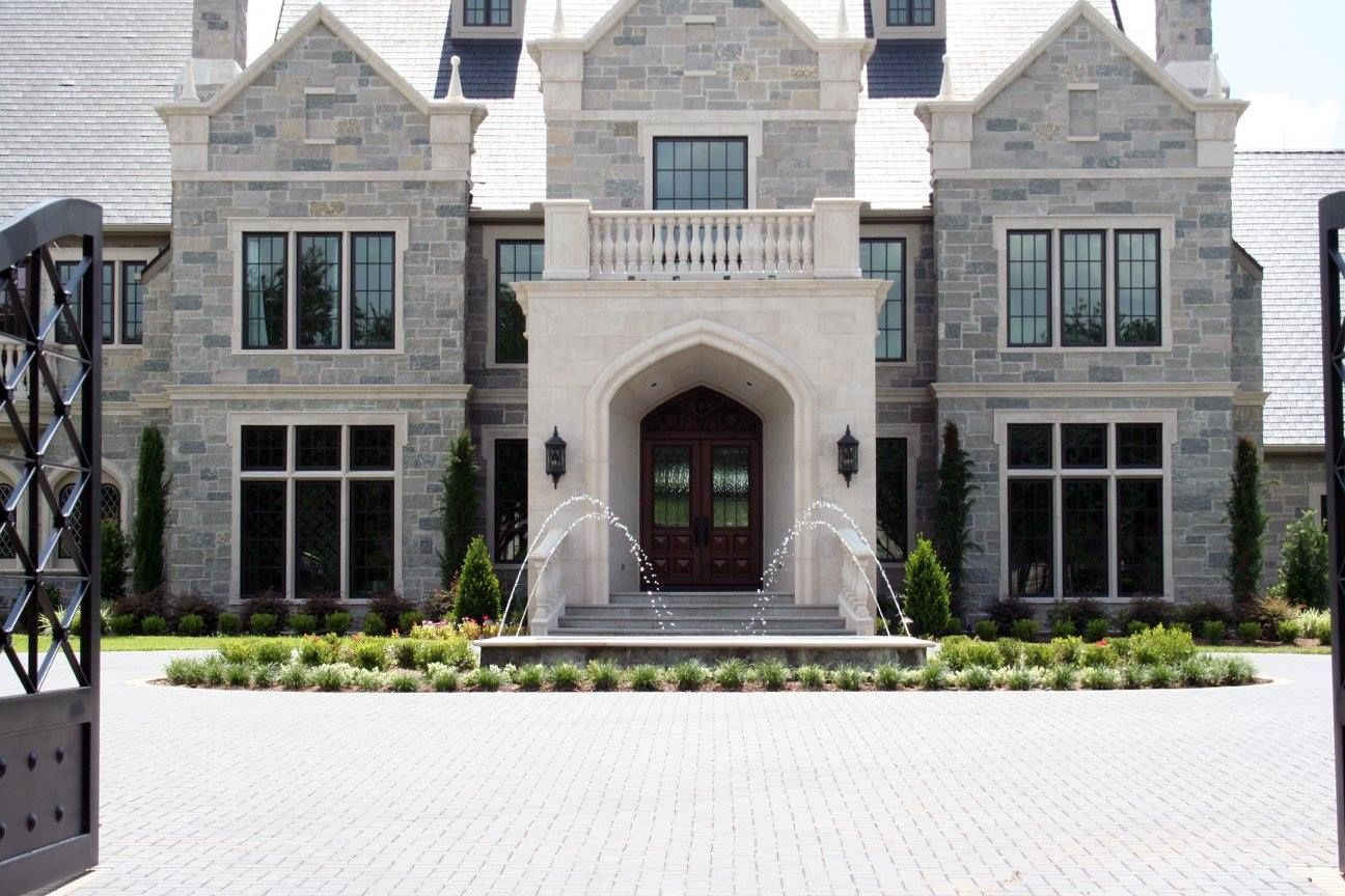 A large stone house with a brick driveway in front of it