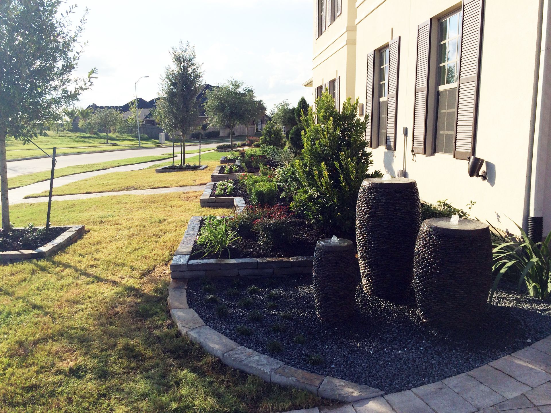 A house with a lush green lawn and a fountain in front of it