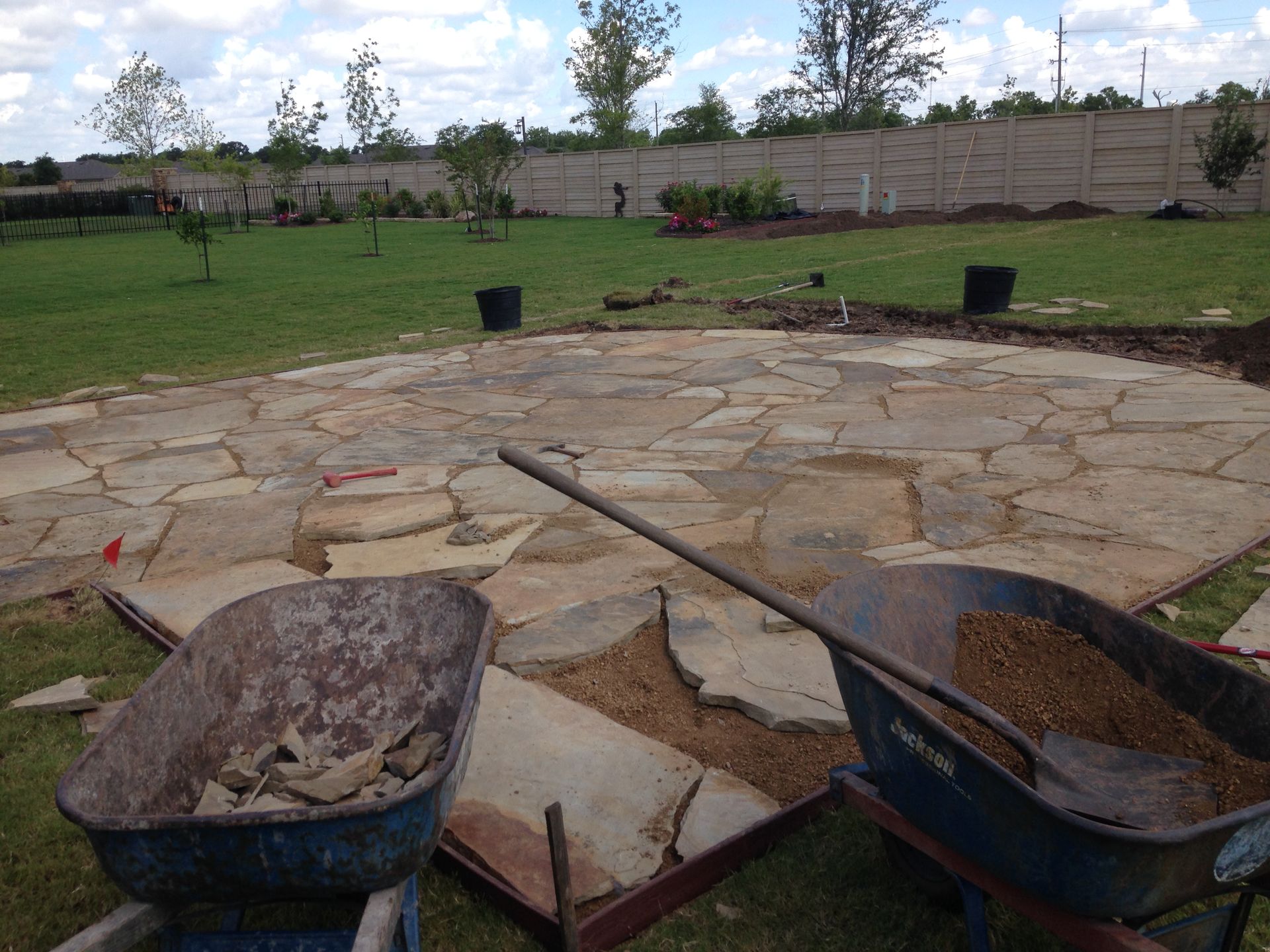 Two wheelbarrows filled with dirt are sitting on a patio.