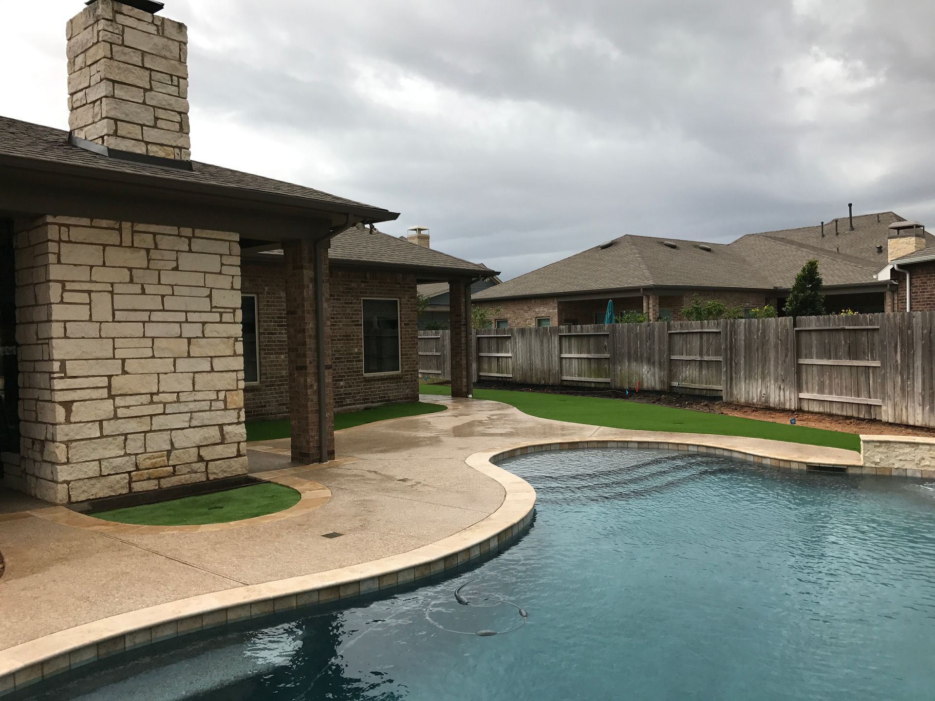 A large swimming pool is in the backyard of a house.