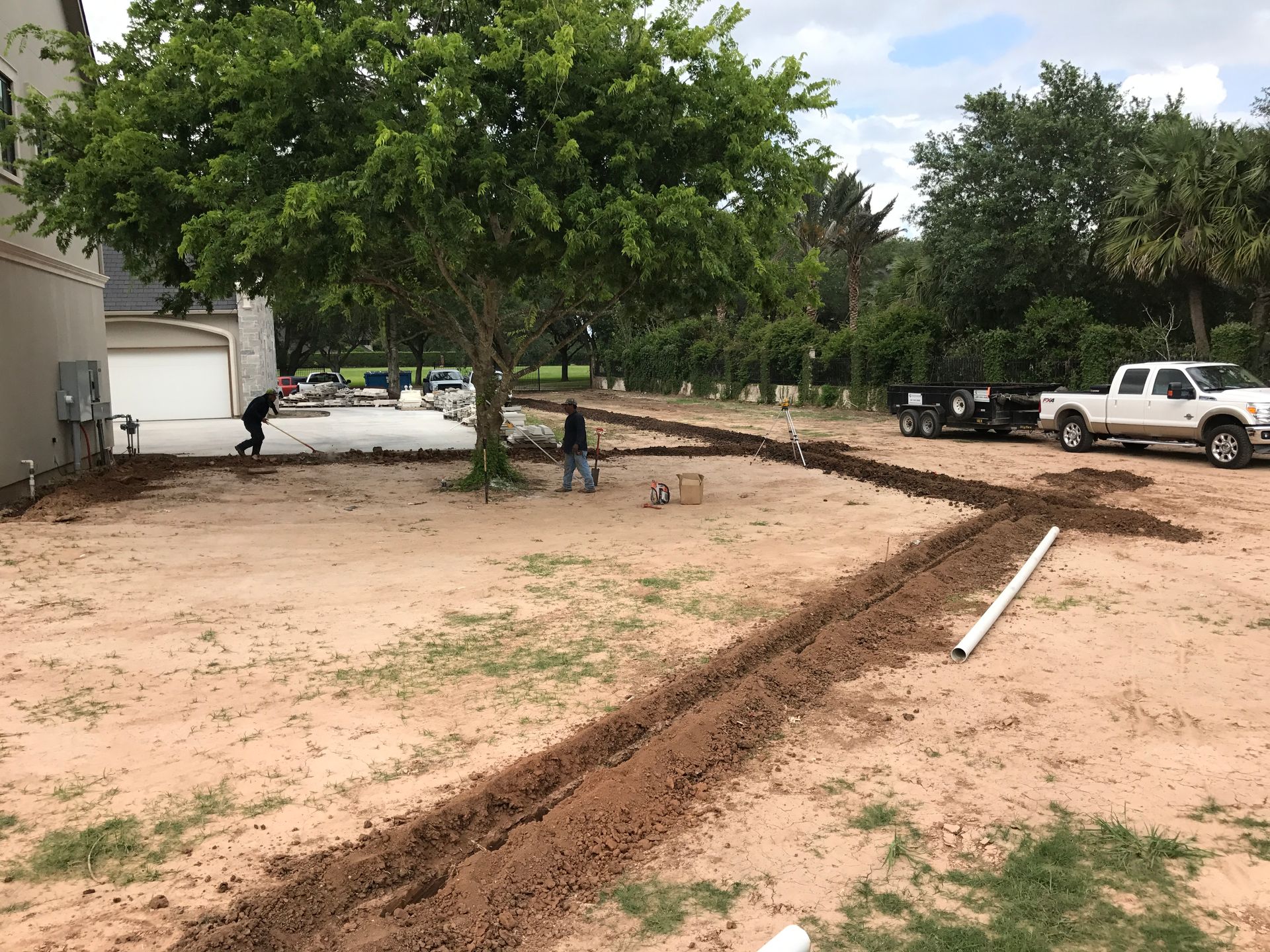 A man is digging a hole in the dirt in front of a house.