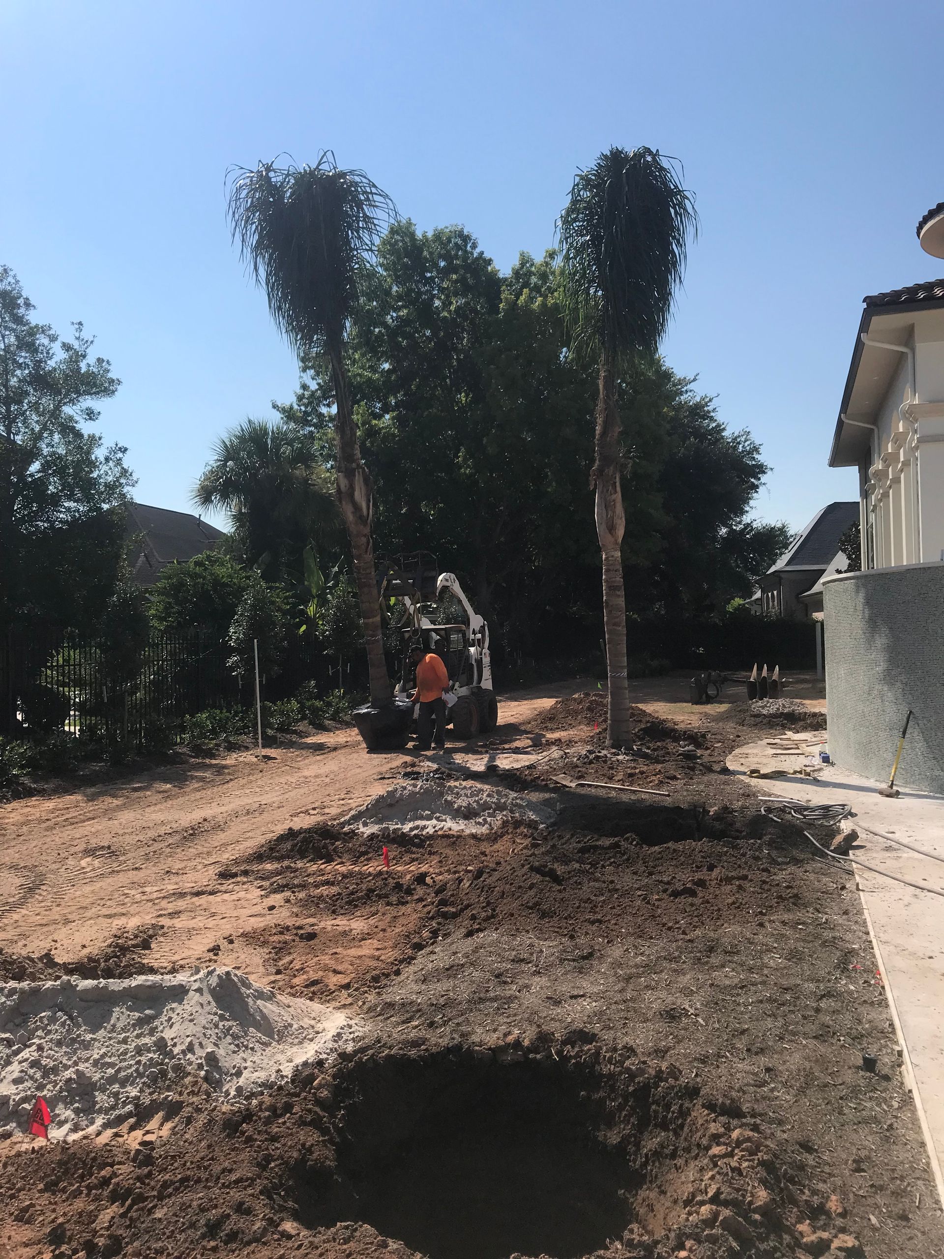 A man is digging a hole in the ground in front of a house