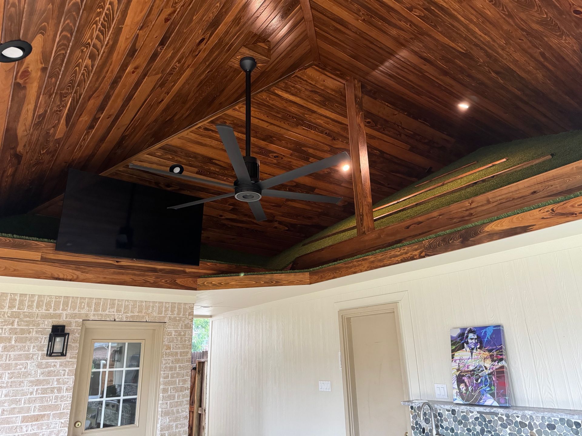 A living room with a wooden ceiling and a ceiling fan.