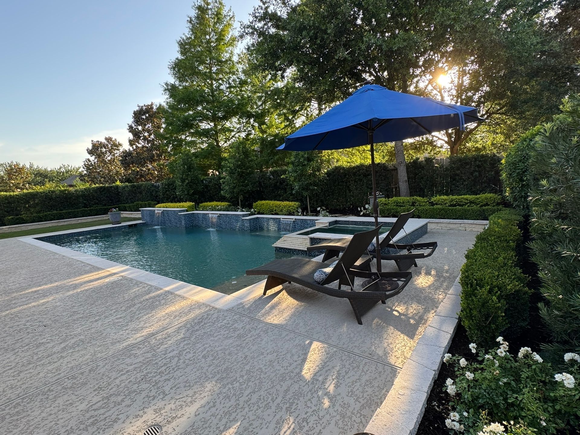 A swimming pool with a blue umbrella and chairs
