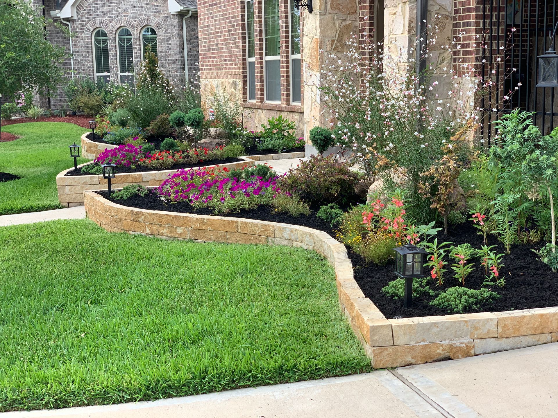 A house with a lush green lawn and a garden in front of it.