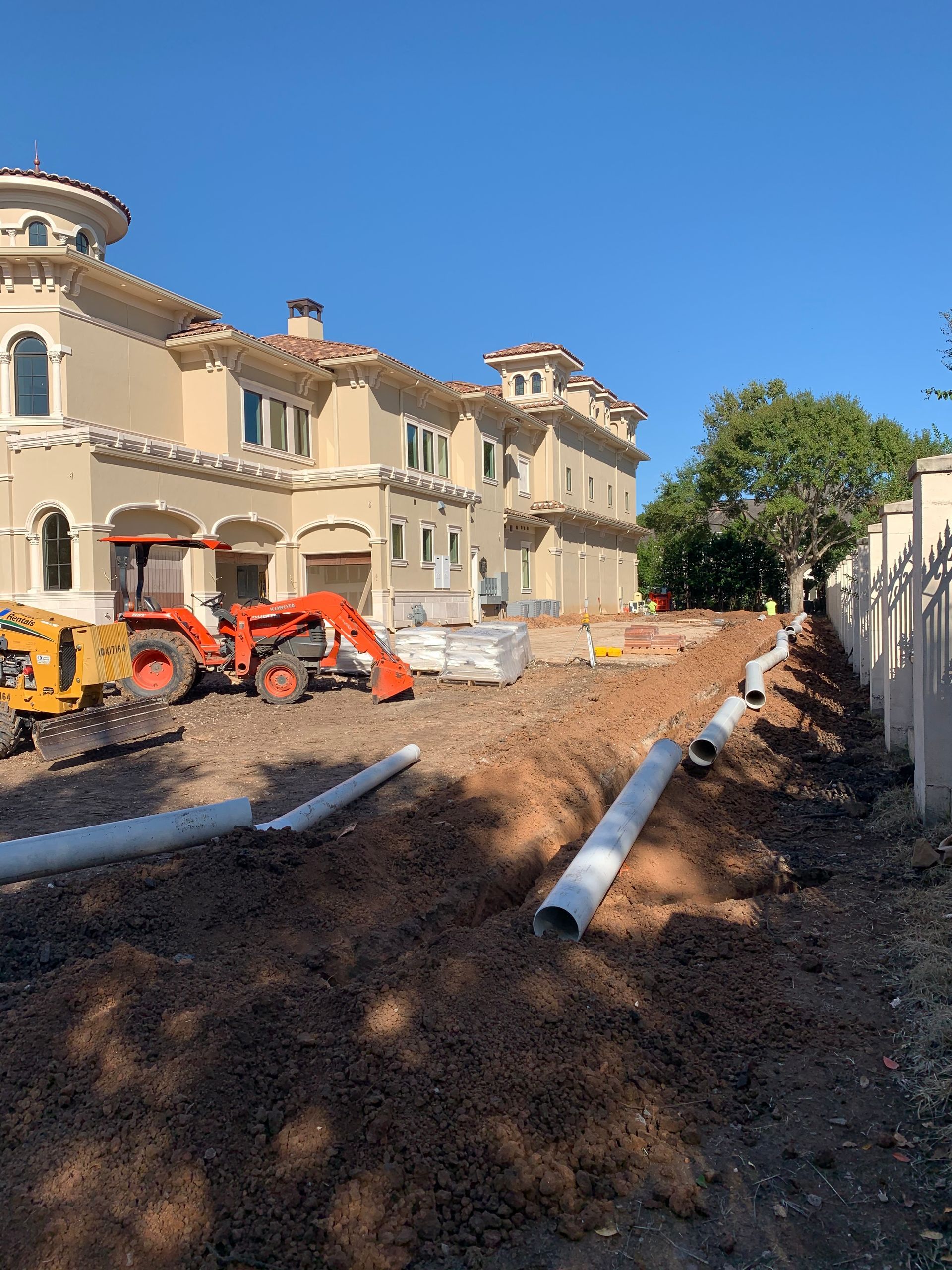 A large house is being built with a lot of pipes in front of it.