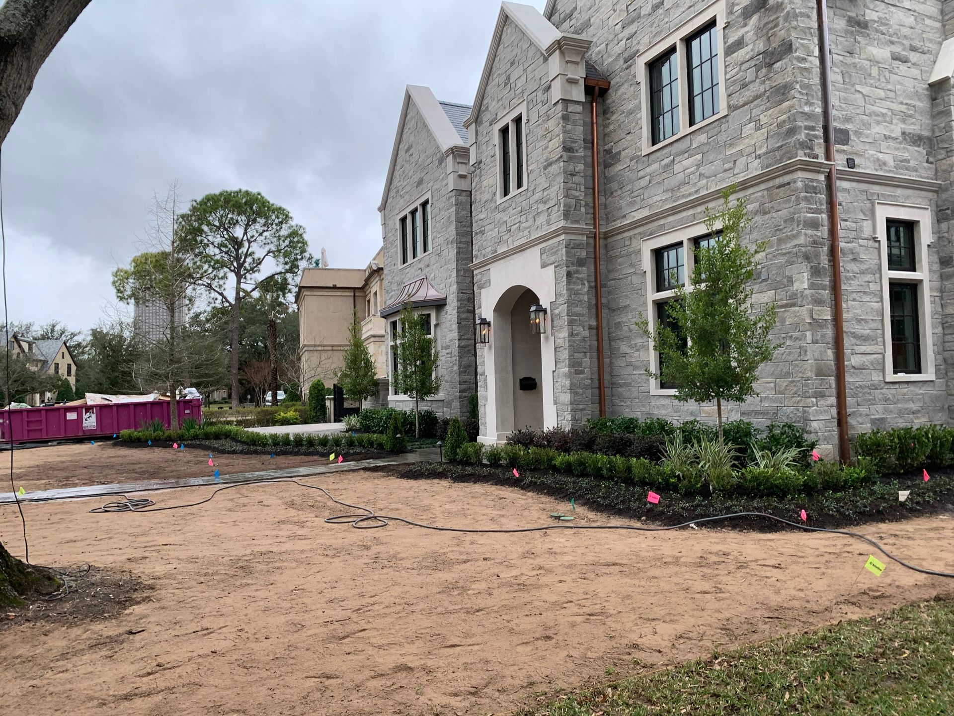 A large brick house with a pink dumpster in front of it.