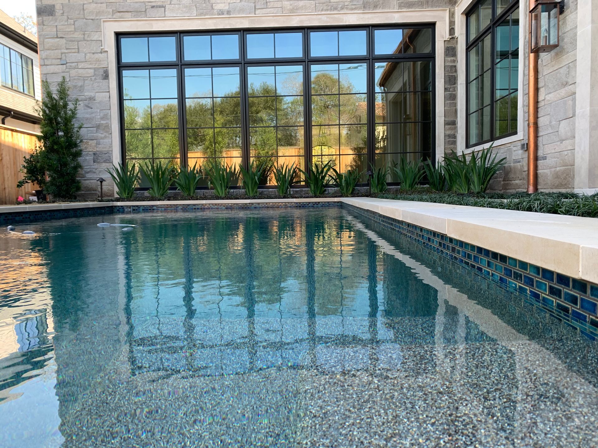 A large swimming pool in front of a house with a lot of windows.