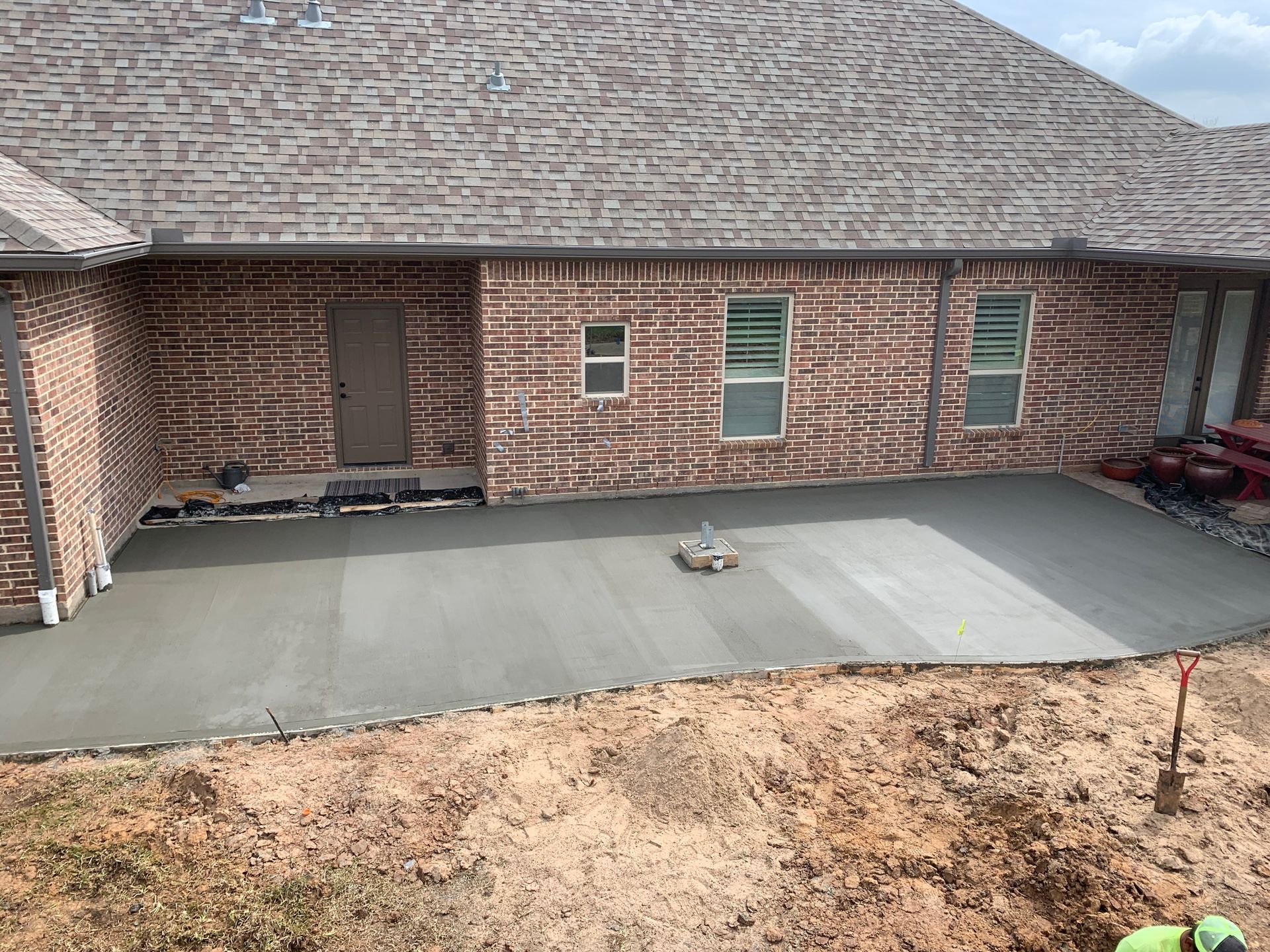 A brick house with a concrete patio in front of it.