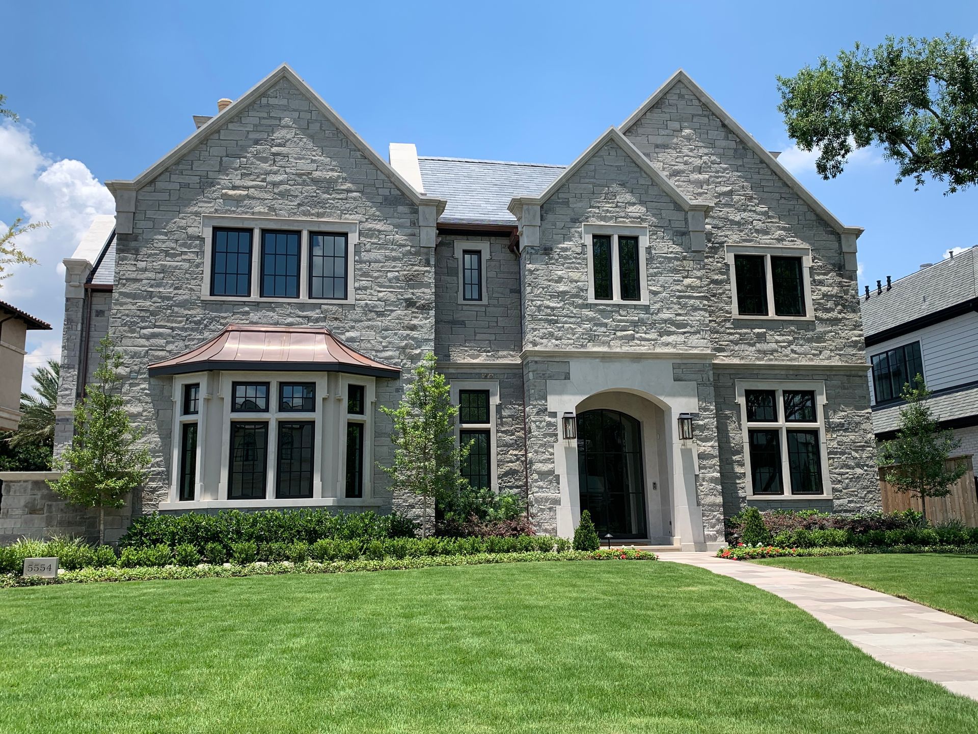 A large stone house with a lush green lawn in front of it