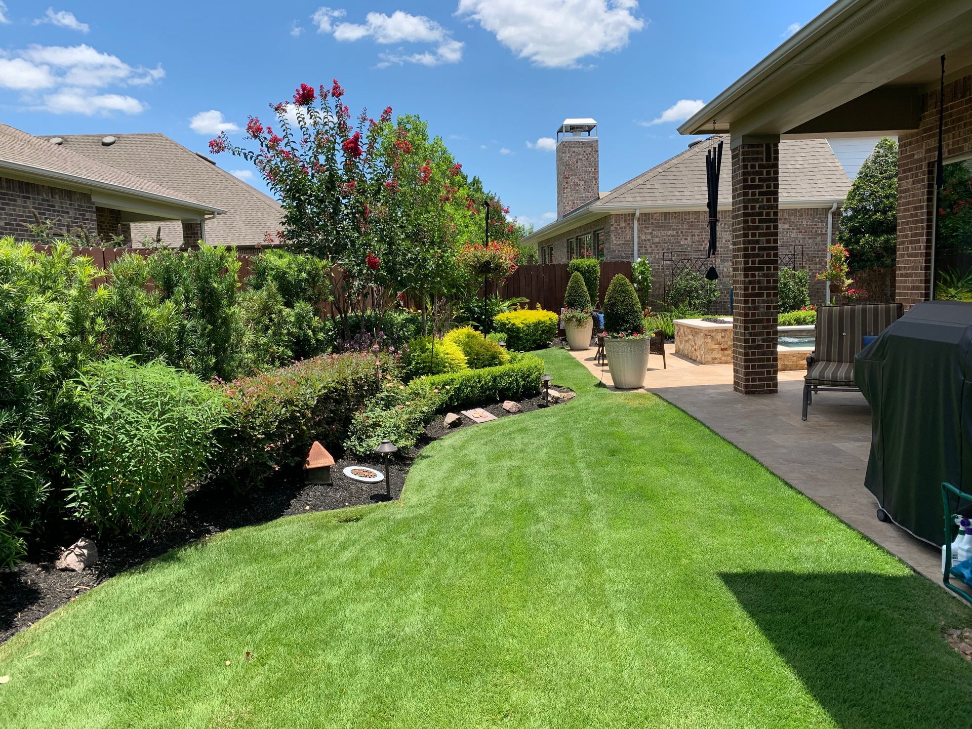A lush green lawn in front of a house with a patio.