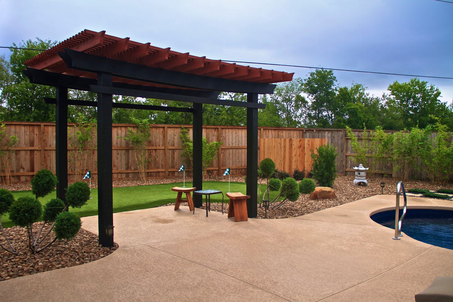 A patio with a pergola and a pool in the background