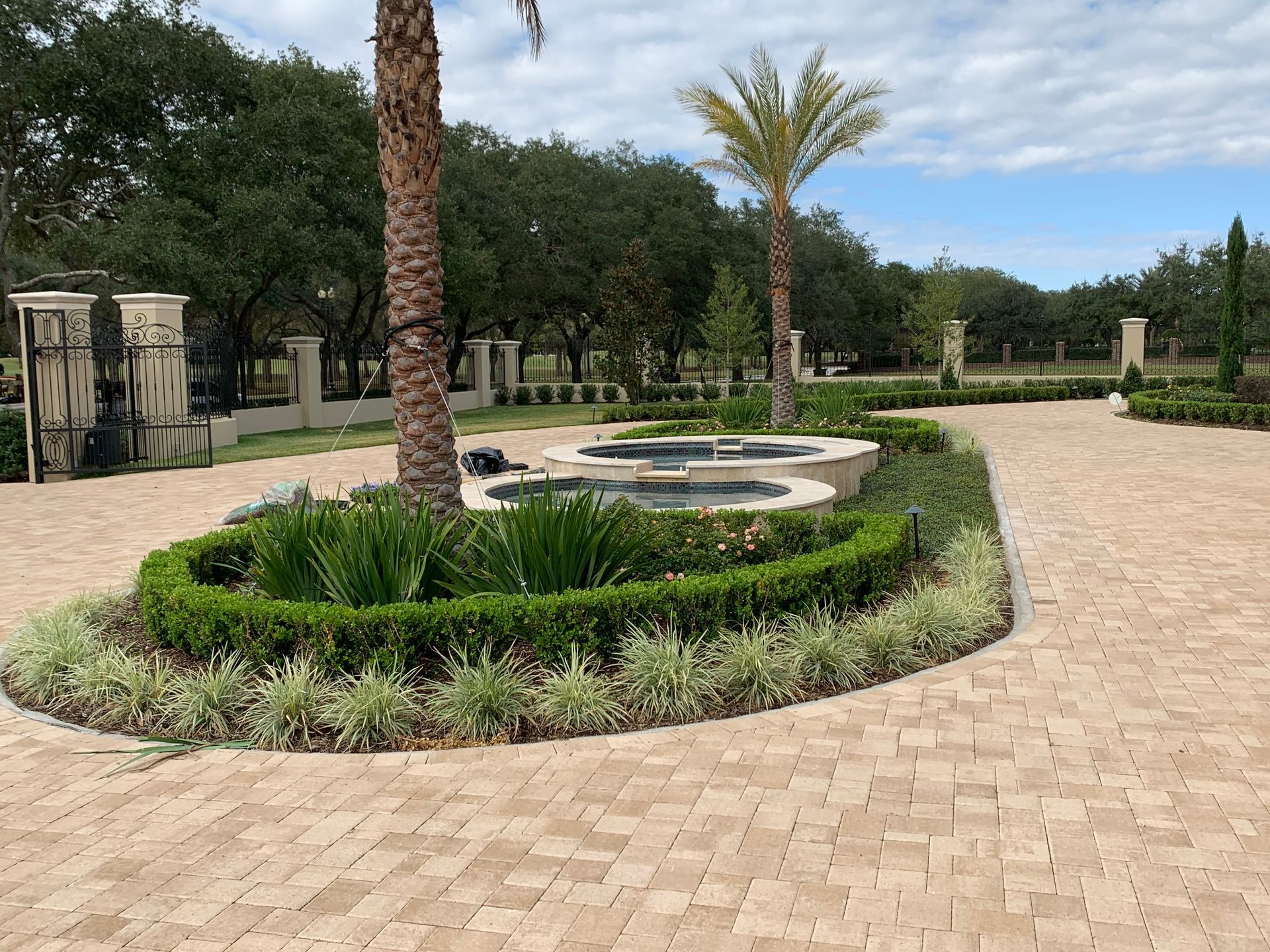 A brick driveway with a fountain in the middle of it