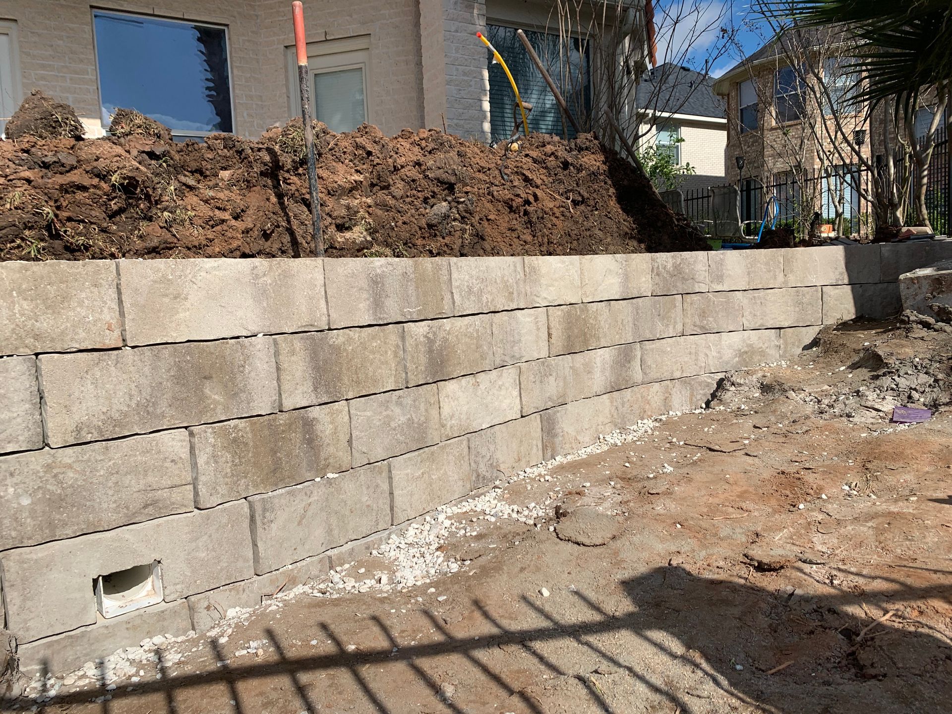 A brick wall is being built next to a pile of dirt.