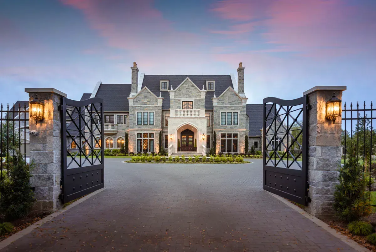A large house with a gated driveway leading to it.