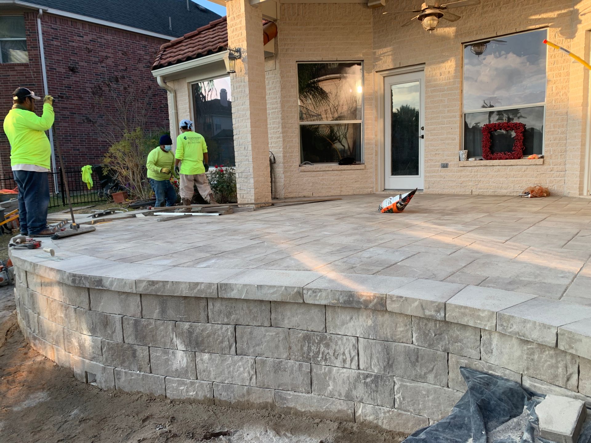 A group of men are working on a patio in front of a house.