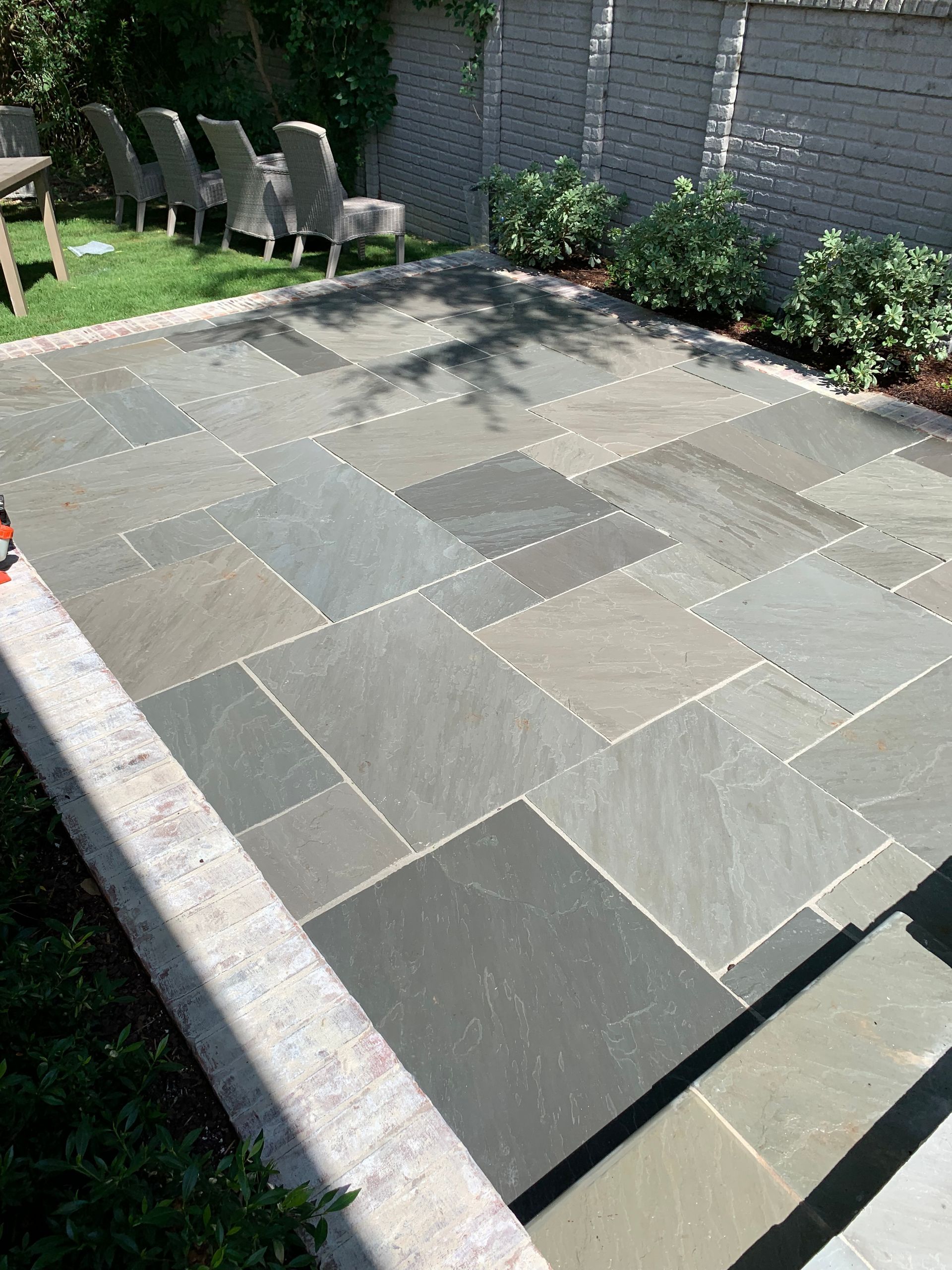 A patio with a lot of tiles and chairs in a backyard.