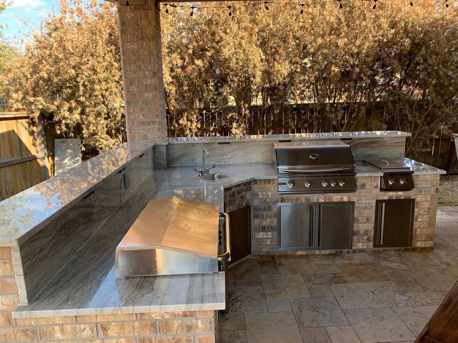 A large outdoor kitchen with a grill and a sink.