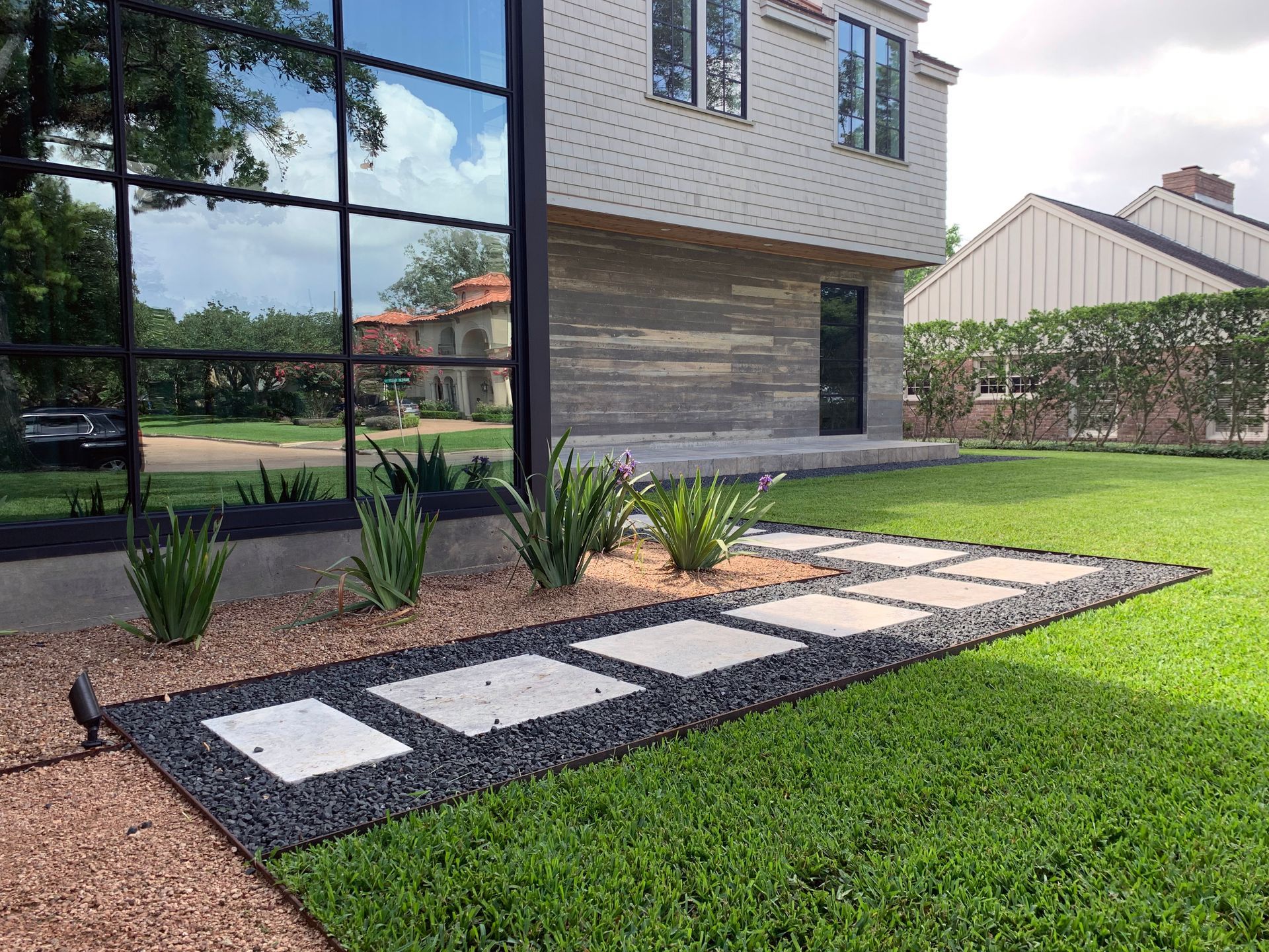 A large house with a lush green lawn and a walkway in front of it.