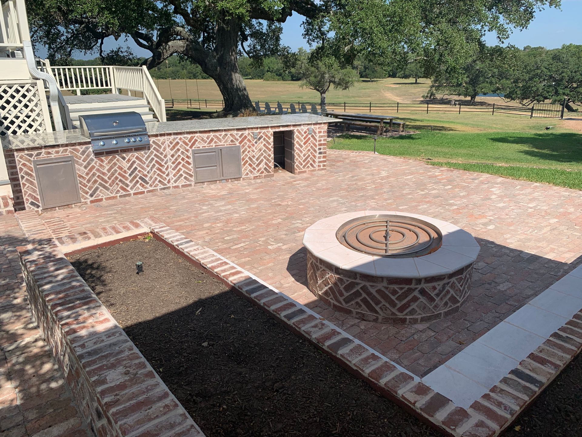 A brick patio with a fire pit and a grill