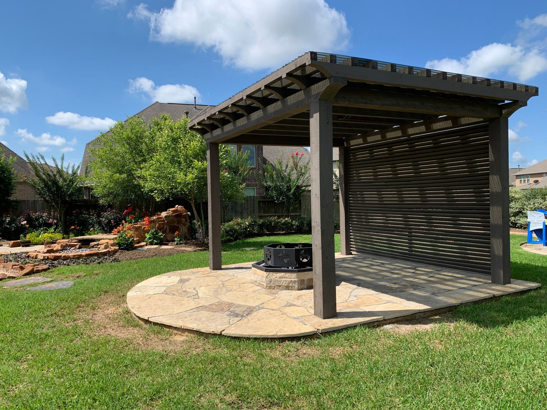 A wooden pergola is sitting on top of a lush green lawn in a backyard.