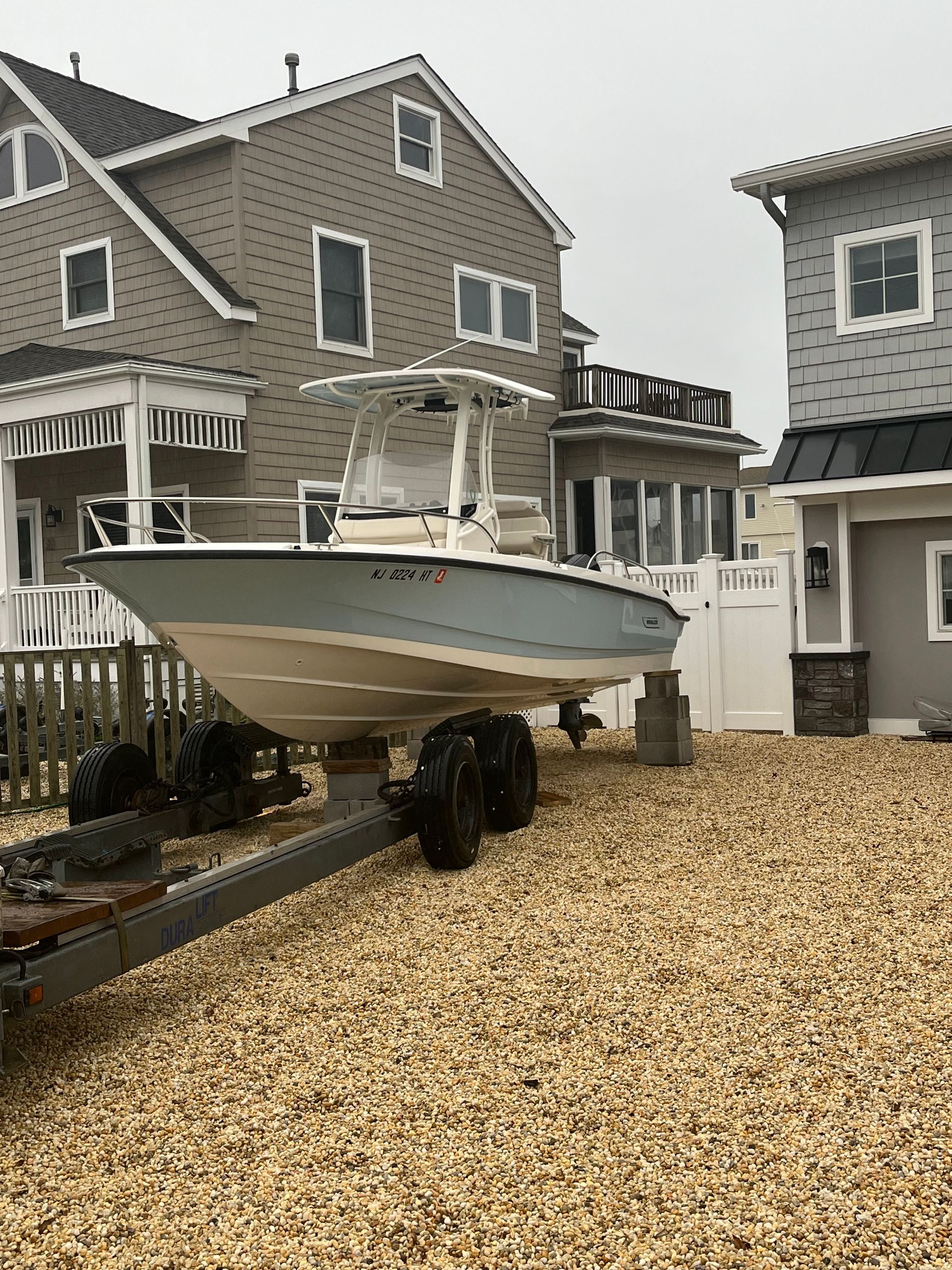 A boat is on a trailer in front of a house.