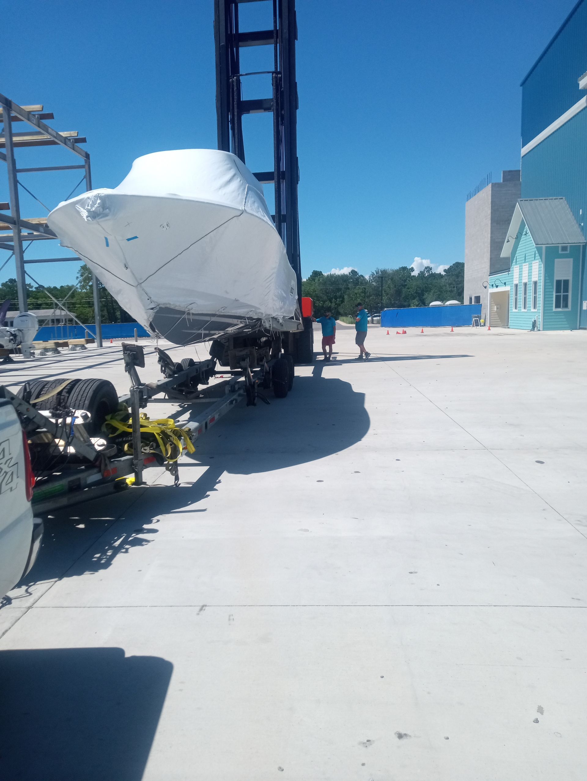 A boat on a trailer is being lifted by a crane