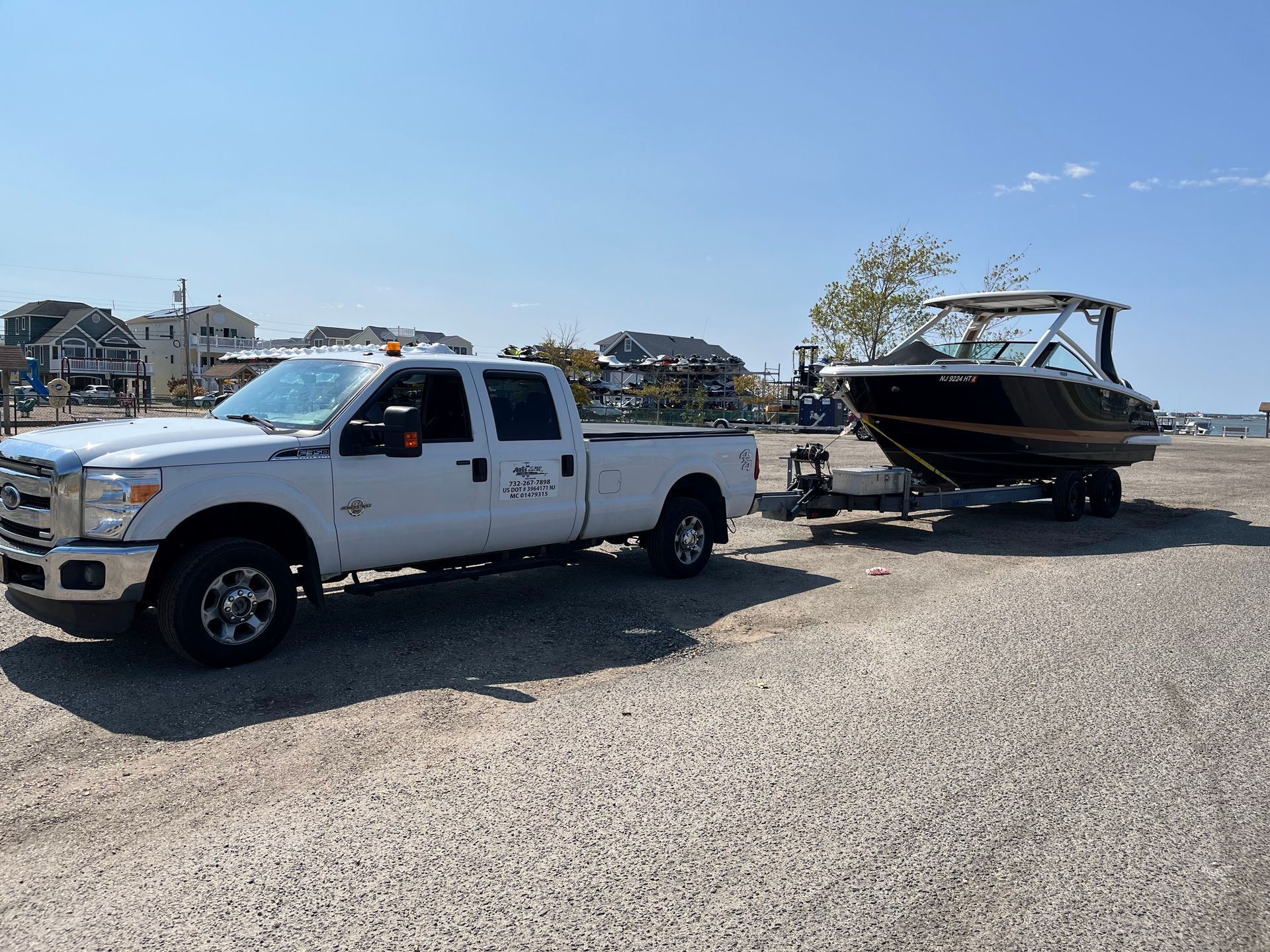 A white truck is towing a boat on a trailer.