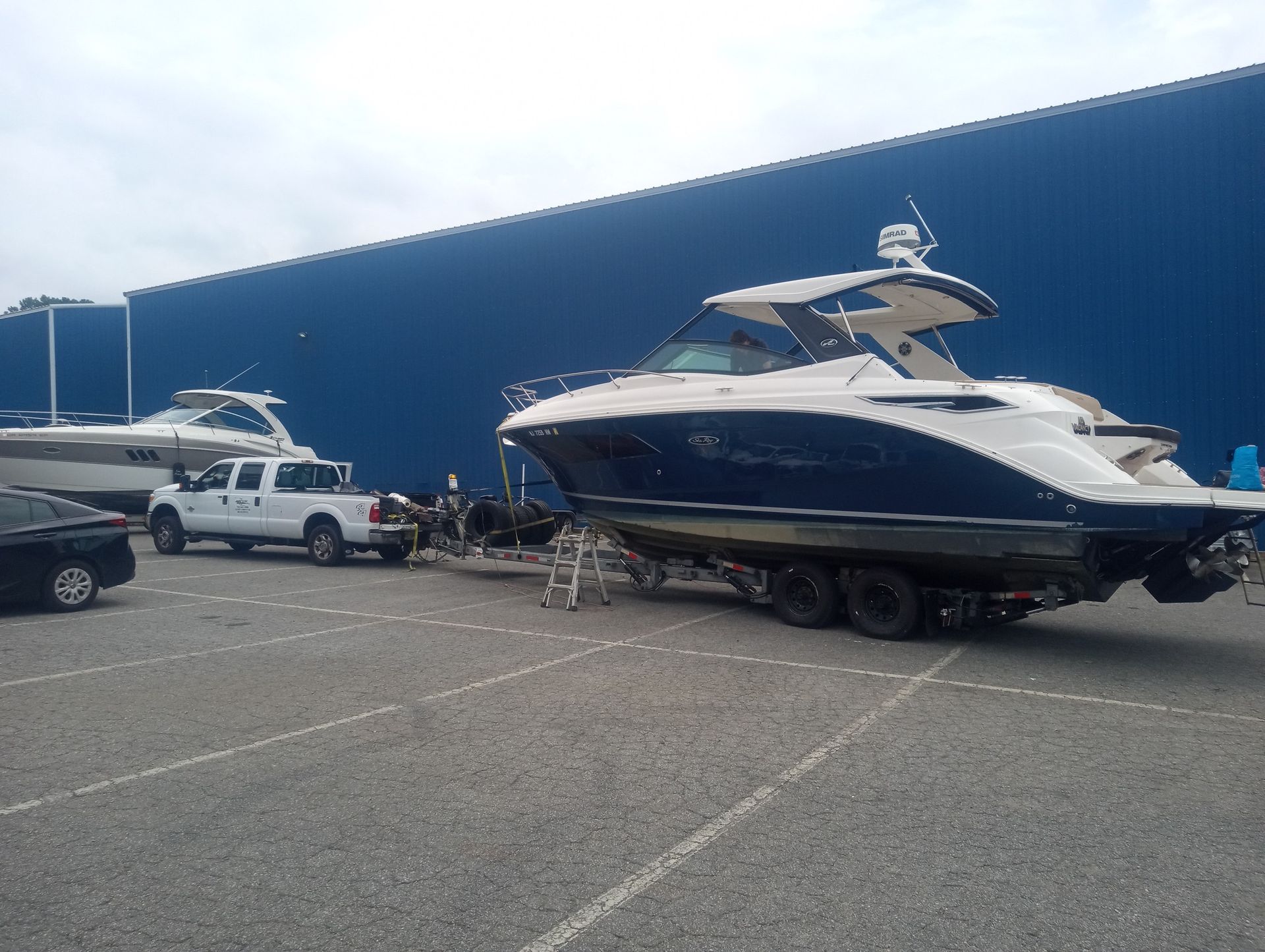 A boat is being towed by a truck in a parking lot.