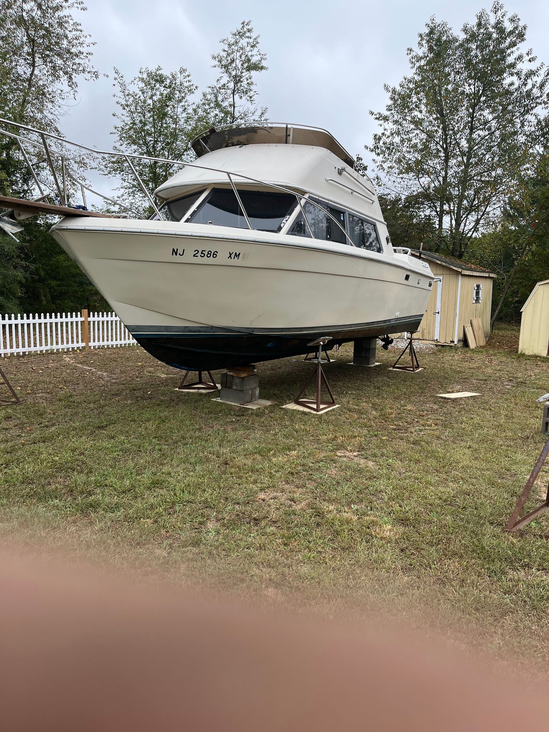 A large white boat is parked in a grassy field.