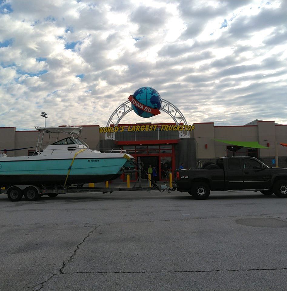 A boat on a trailer is parked in front of a building that says 