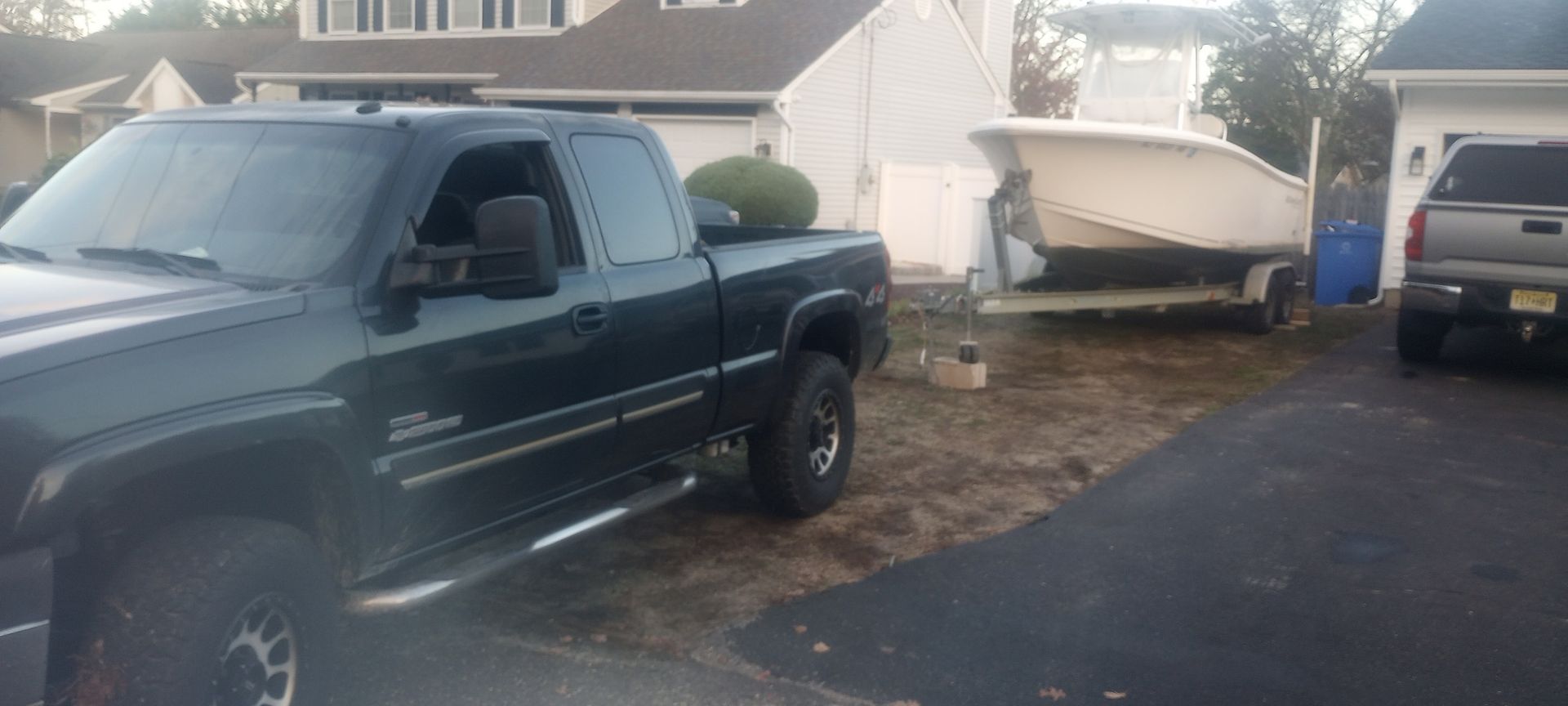A truck is parked in front of a house with a boat on the trailer.